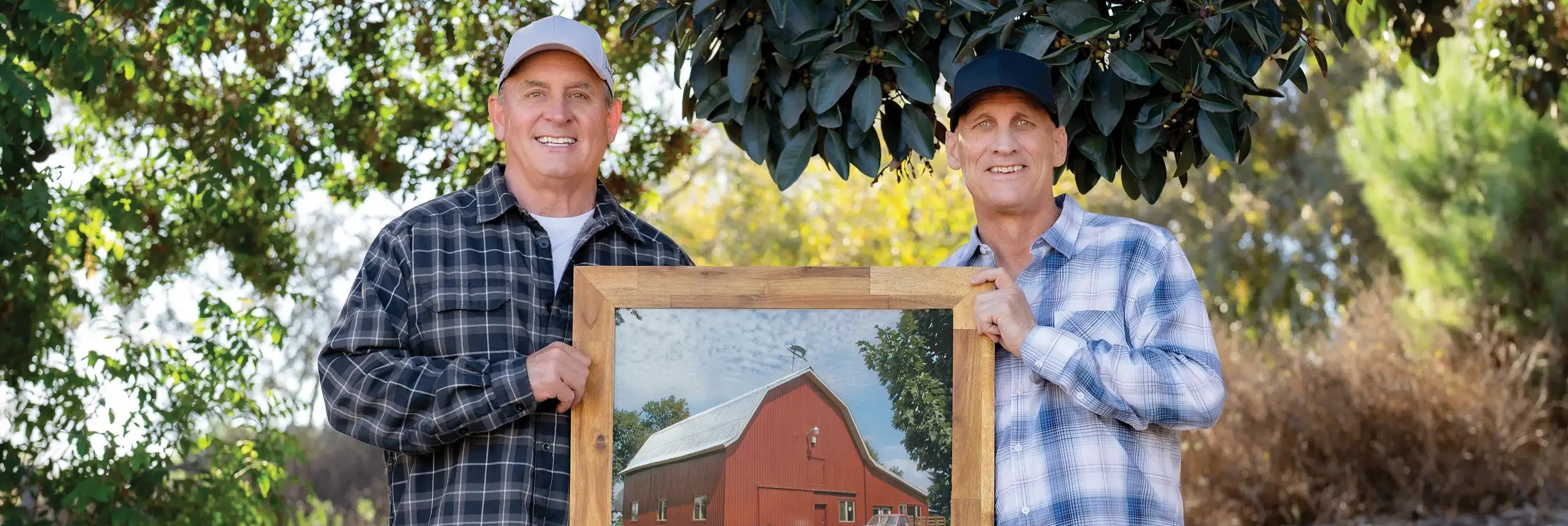 Jeff and Howie holding a framed picture of the original red barn